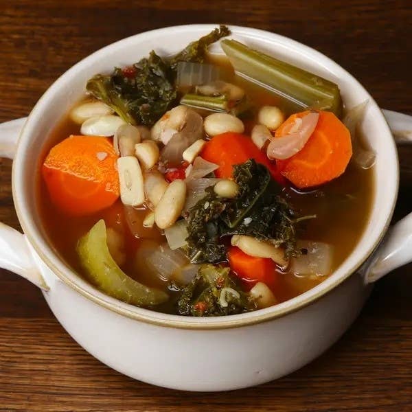 Vegetable soup with beans, carrots, and greens in a white bowl
